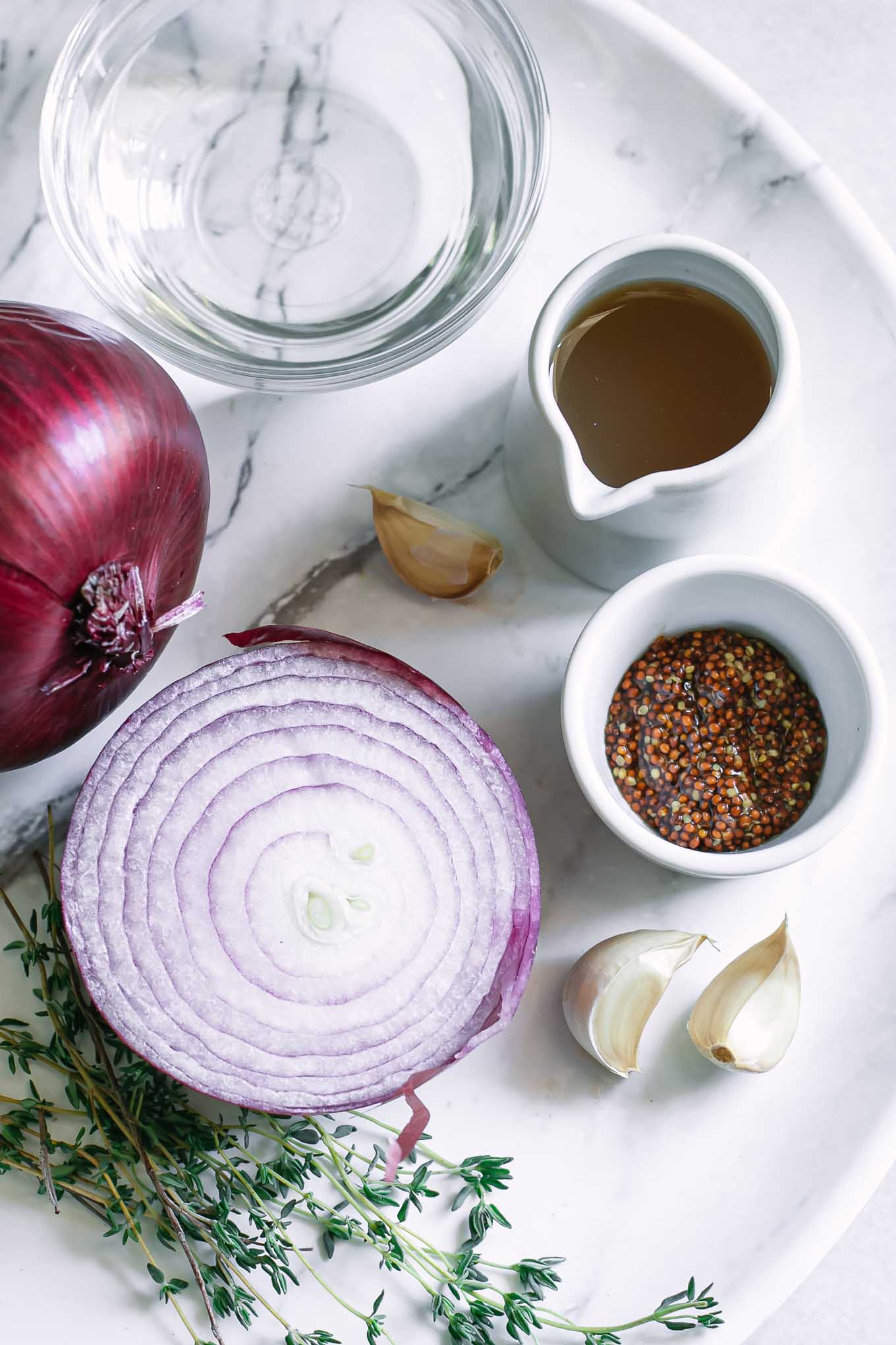 a plate containing red onions, water, oil, garlic, herbs and spices