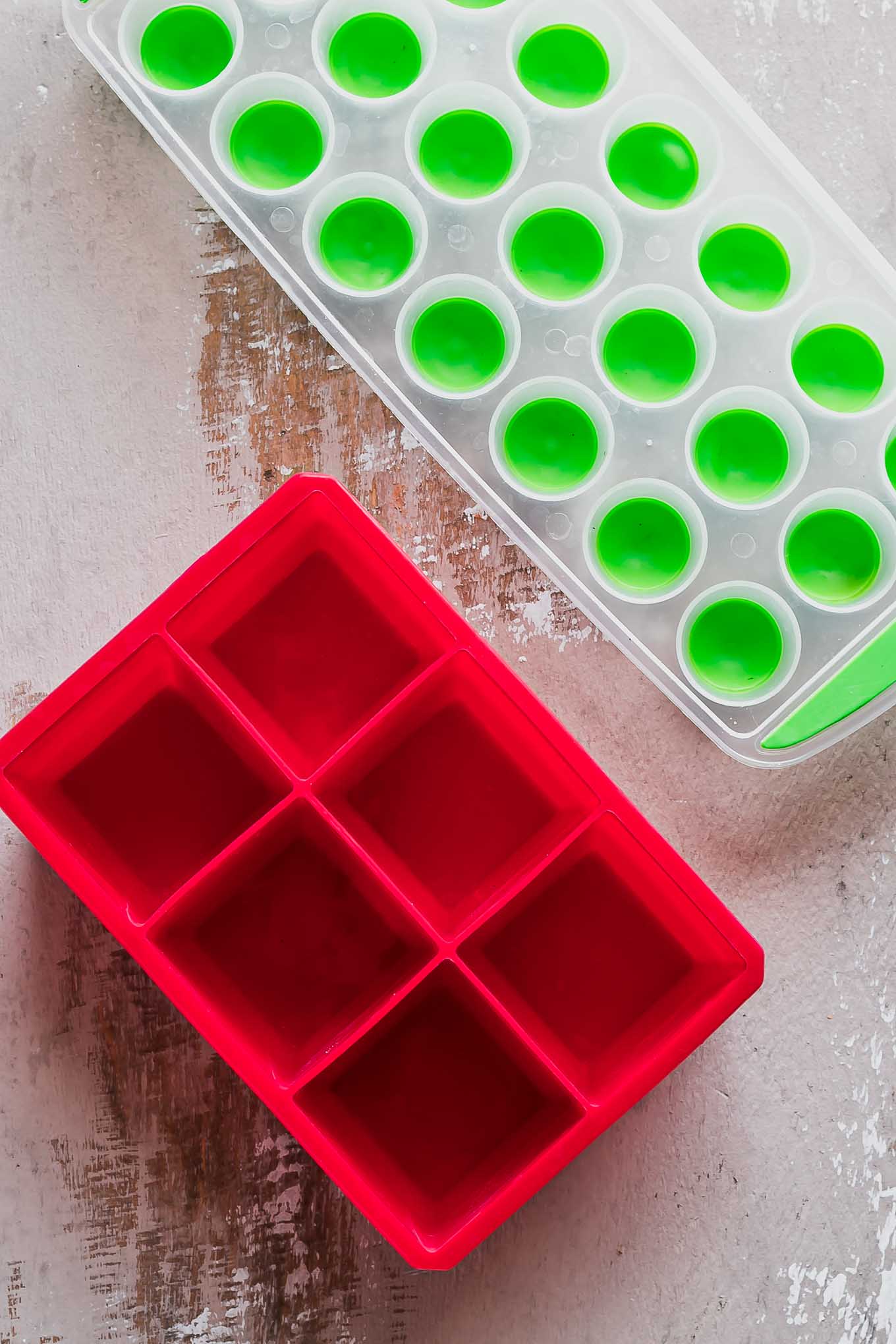 red and green silicone ice trays on a wooden table