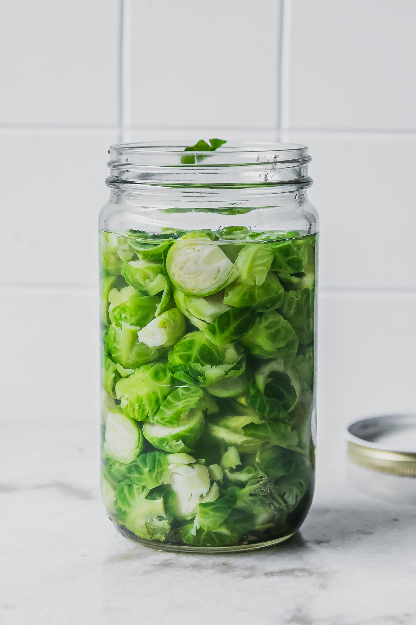 pickled brussels sprouts in a jar on a white countertop