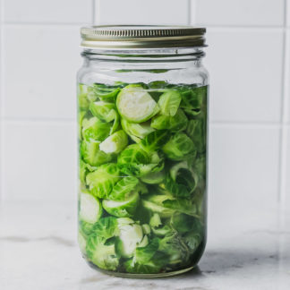 a jar of pickled brussels sprouts on a white table