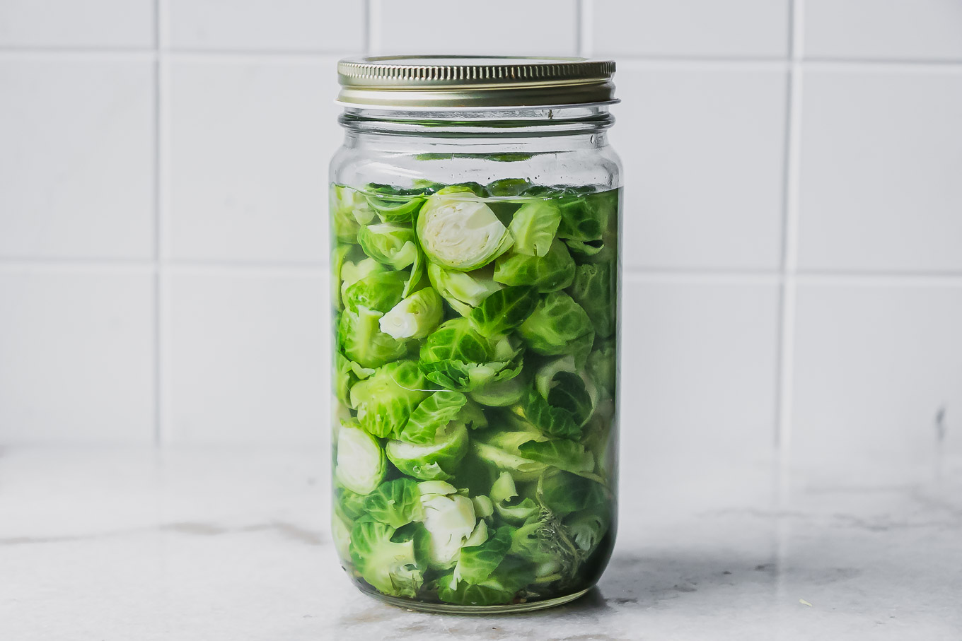 a jar of pickled brussels sprouts on a white table