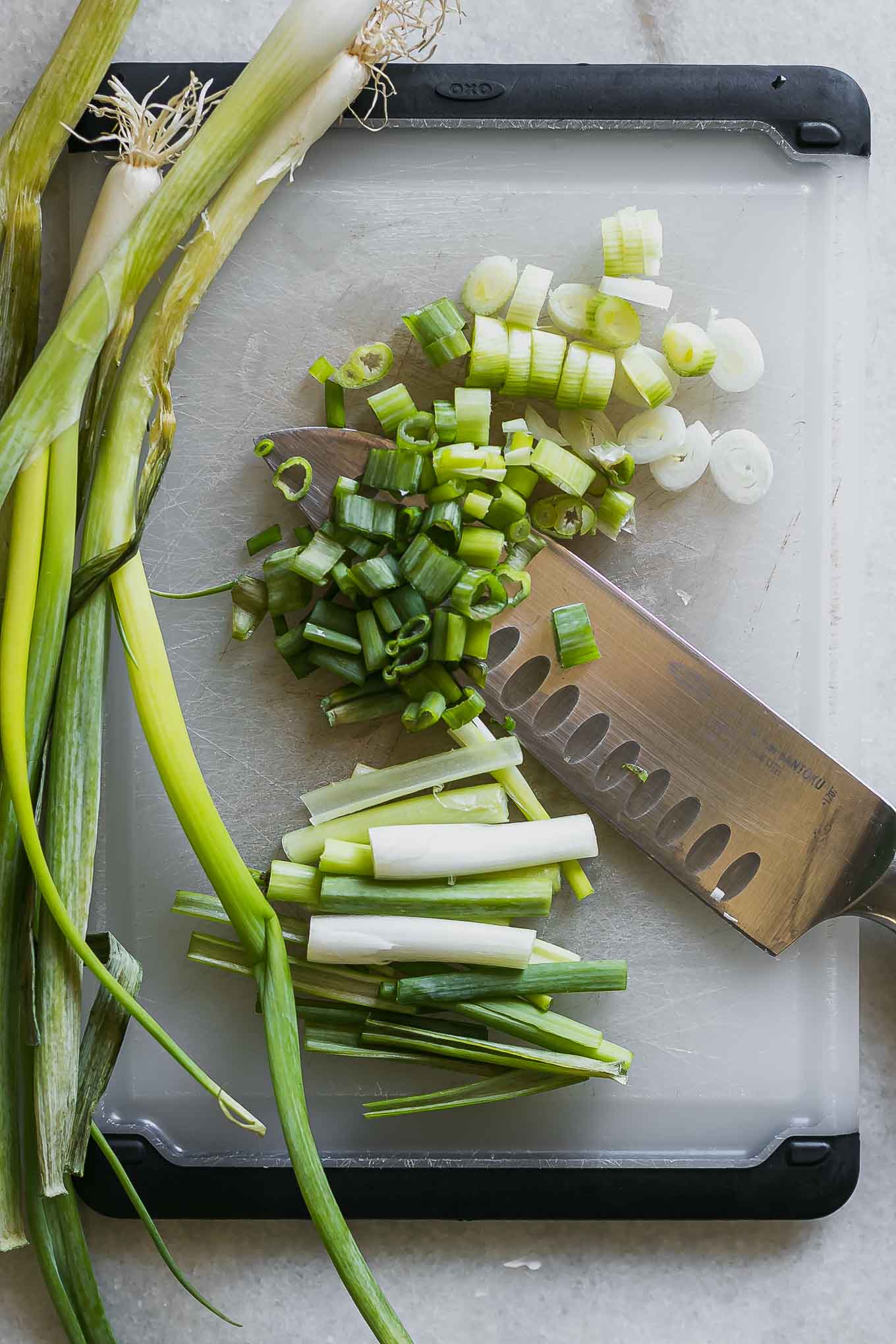 sliced and cut spears of green onions on a cutting board