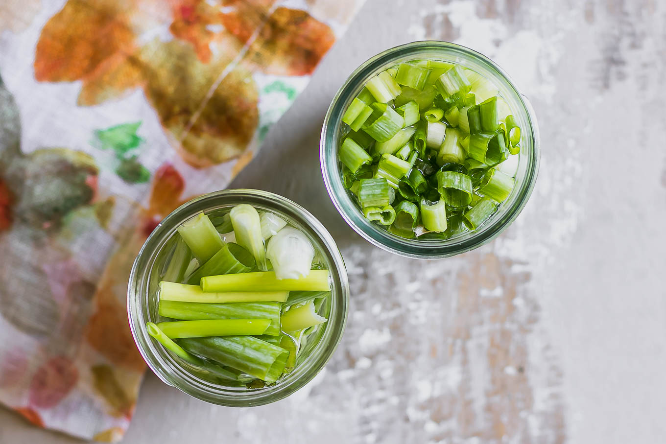 two jars of pickled scallions on a wood table