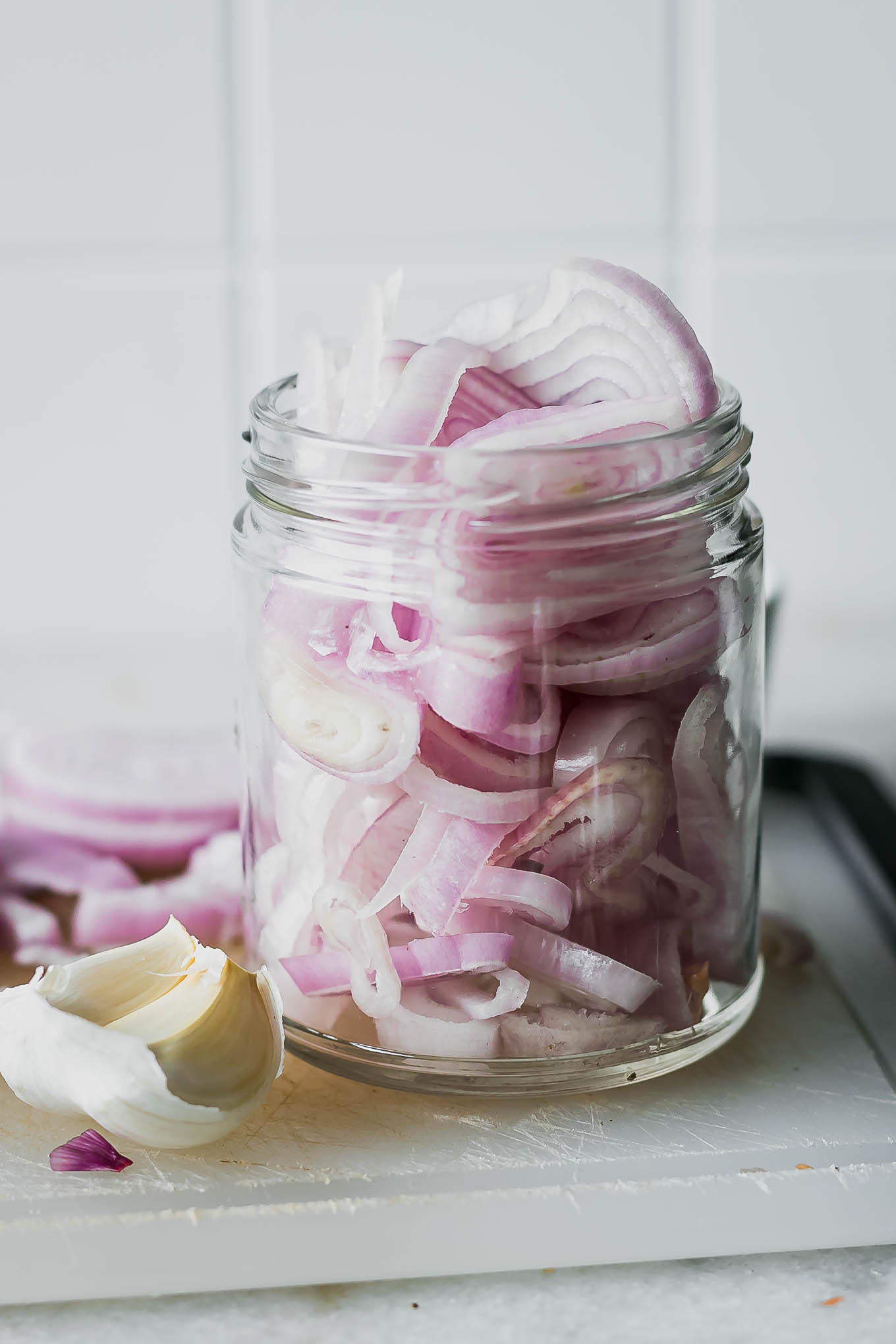 sliced shallots in a jar on a white countertop