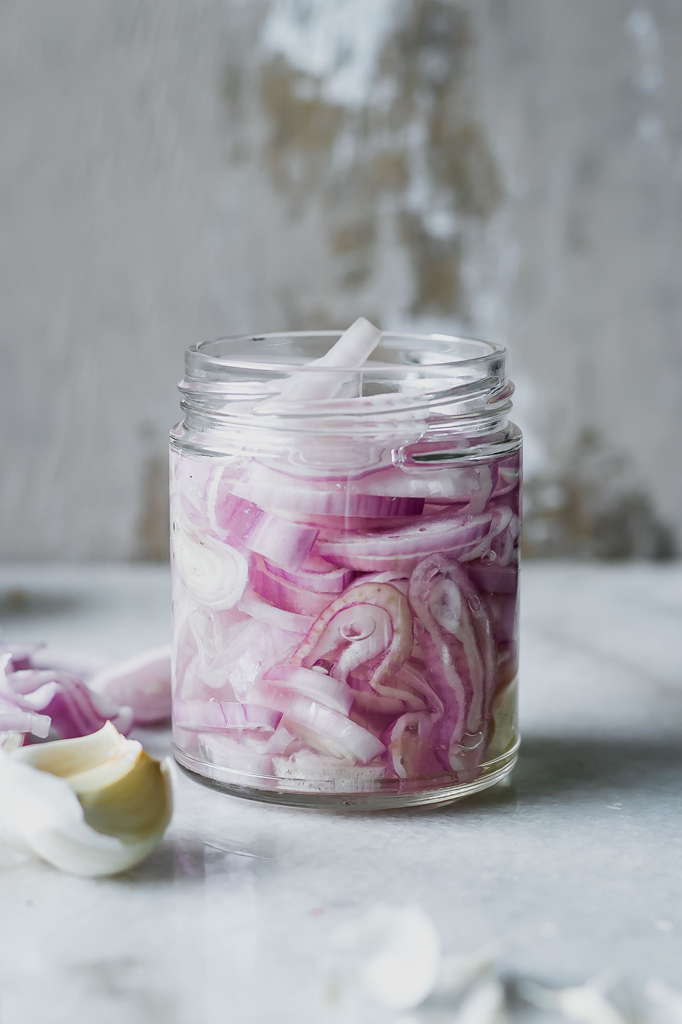 sliced shallots in a jar with pickling brine on a white countertop