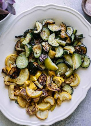 roasted sliced zucchini and yellow summer squash on a white plate