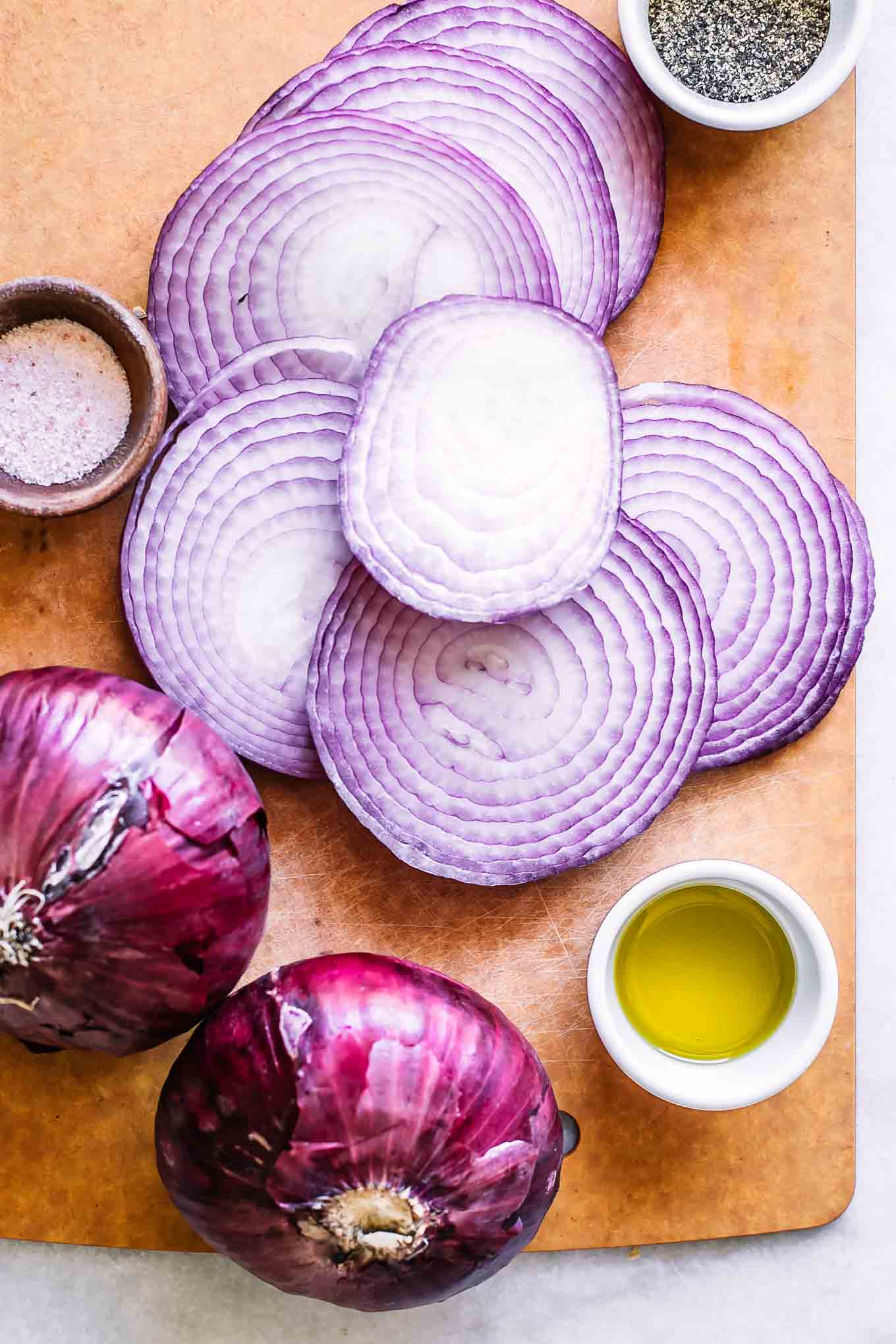 sliced red onions on a wood cutting board
