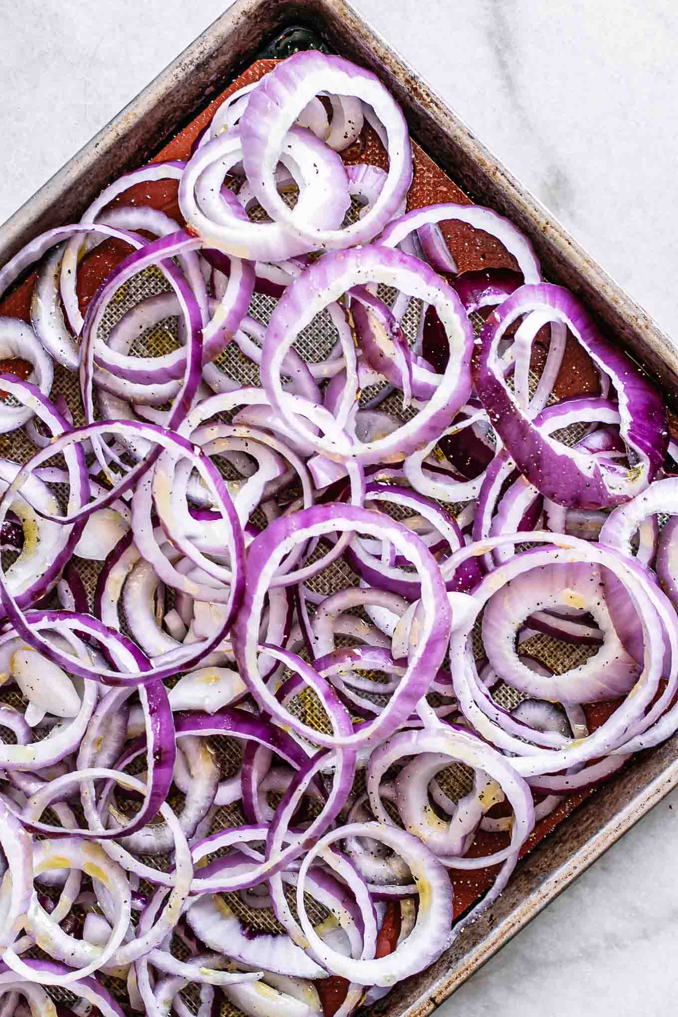 sliced red onions on a roasting pan before baking