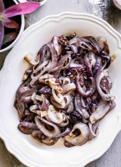 roasted red onions on a white plate on a wood table