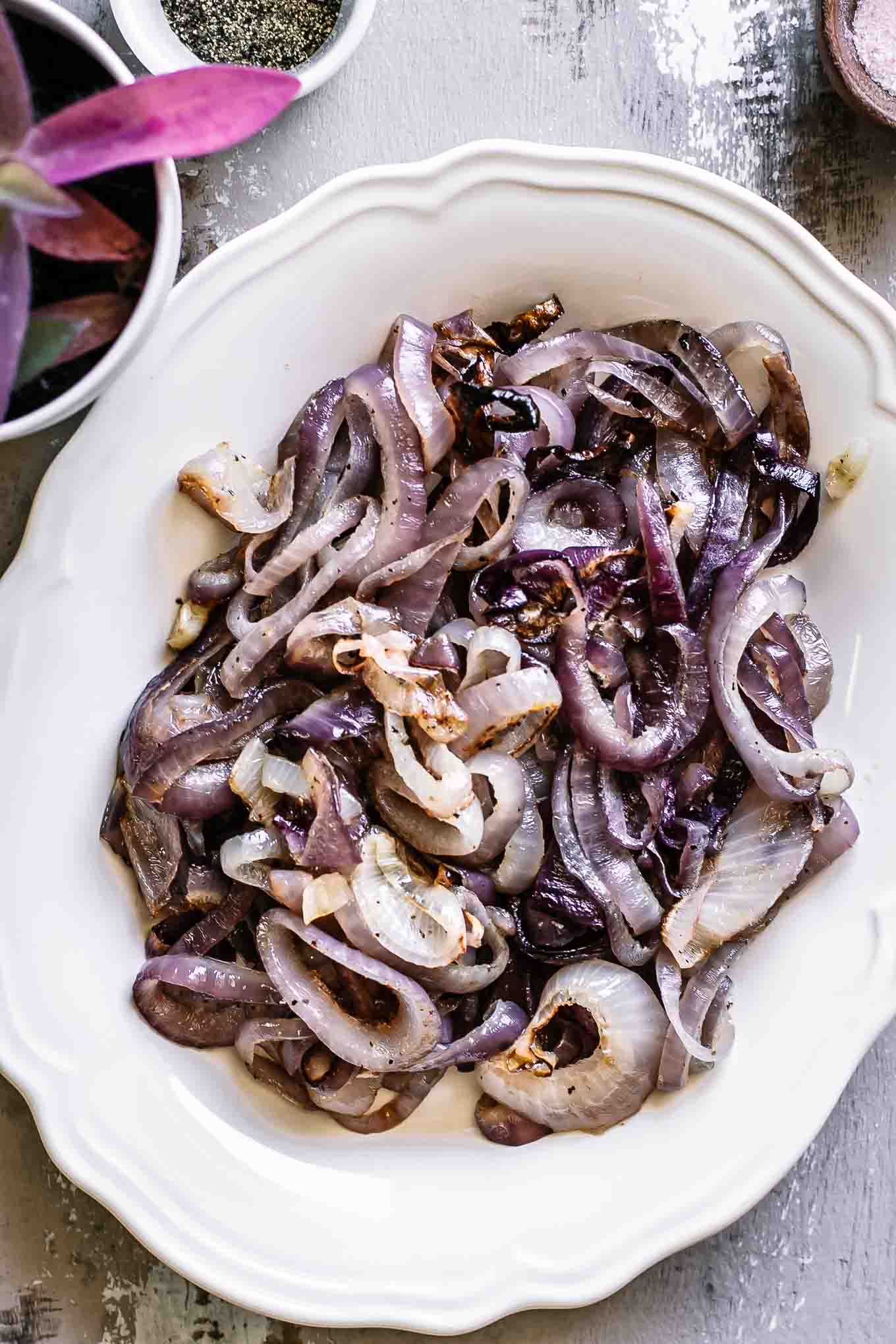 roasted red onions on a white plate on a wood table