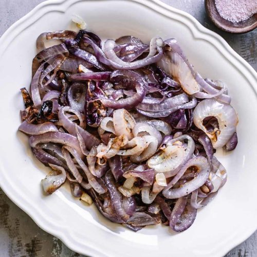 roasted red onion slices on a white plate on a white table