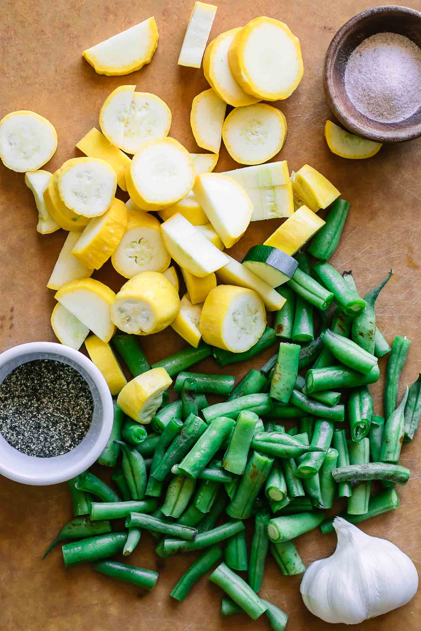 sliced yellow summer squash and cut green beans on a cutting board