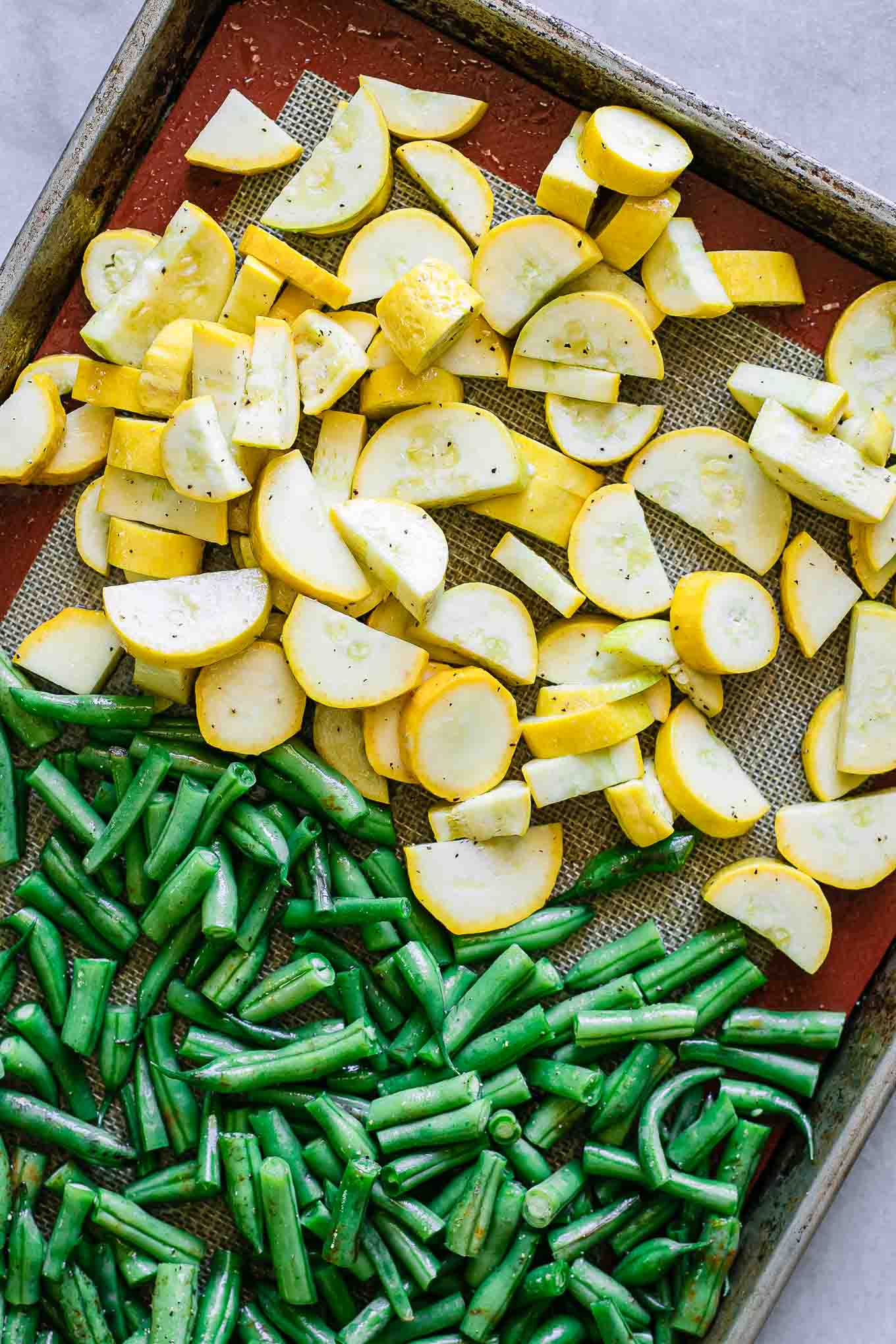 green bean and summer squash slices on a pan before roasting