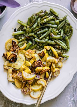 roasted yellow summer squash and green beans slices on a white serving plate