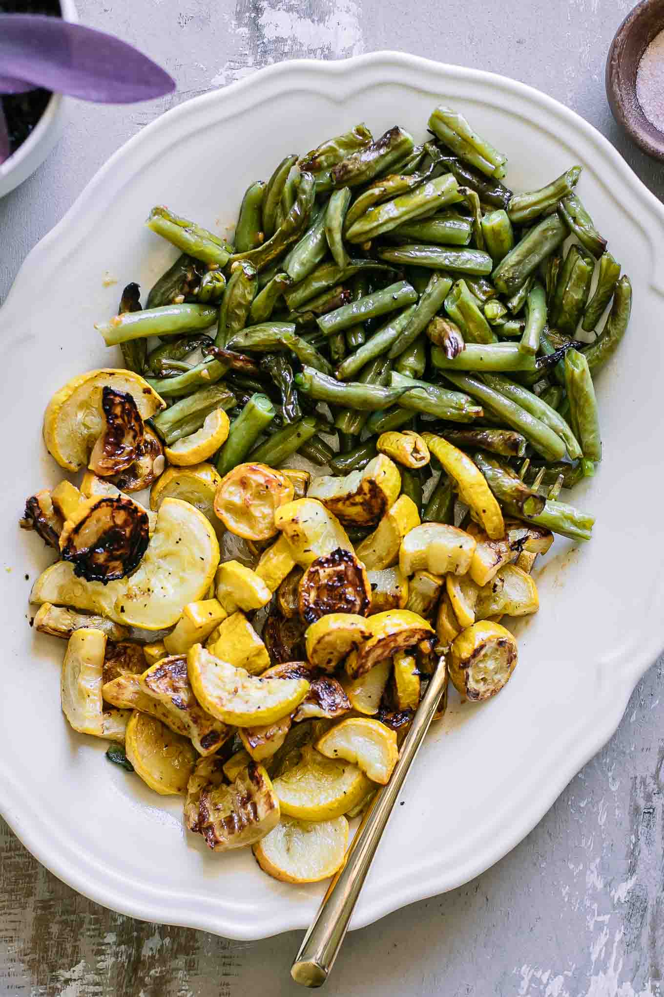 roasted yellow summer squash and green beans slices on a white serving plate