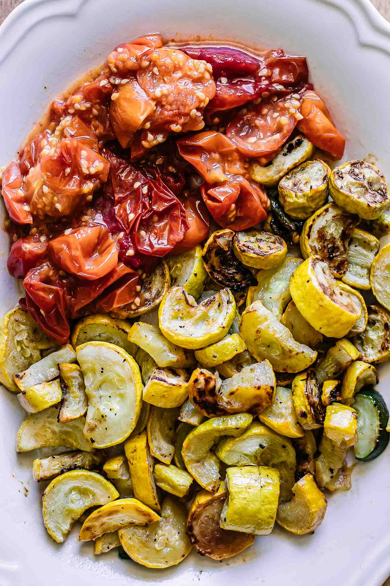 baked tomatoes and yellow squash on a white plate