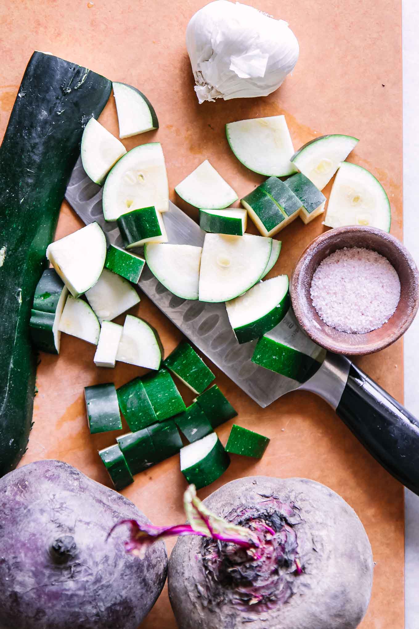 sliced zucchini and beets on a cutting board with a knife