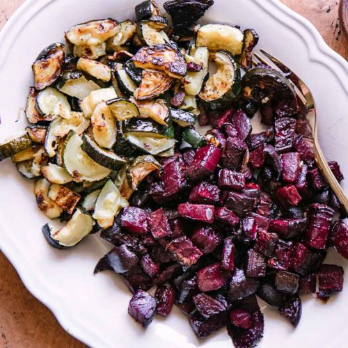 roasted beets and zucchini on a white plate with a gold fork