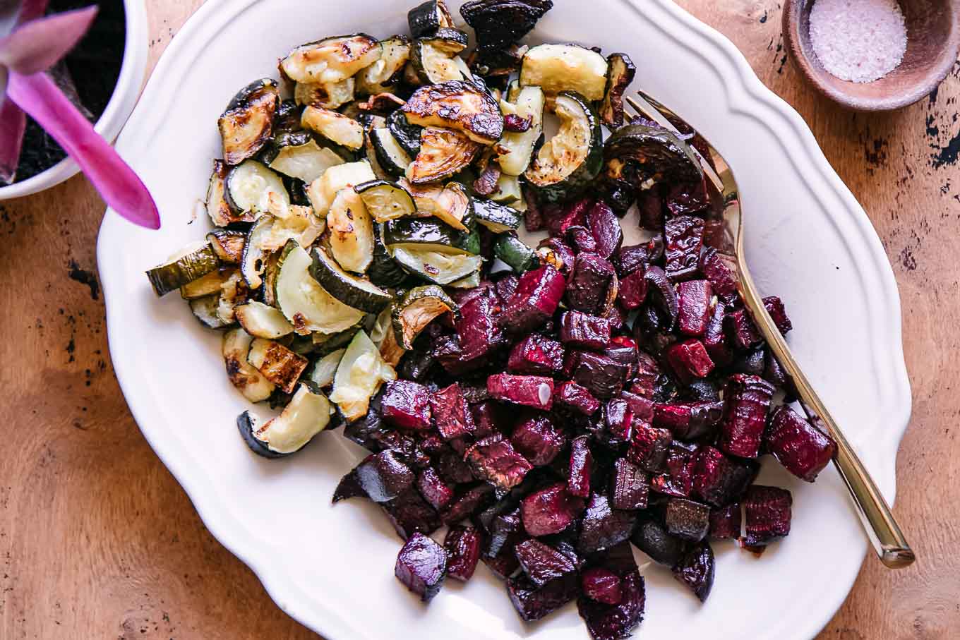 baked zucchini and beets on a white plate on a wood table