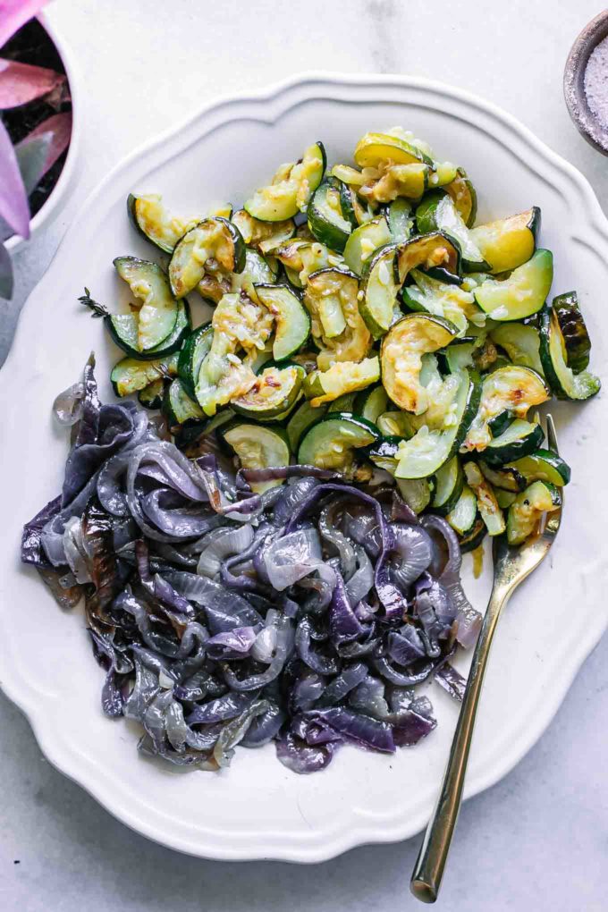 roasted zucchini and red onions on a white plate on a white table