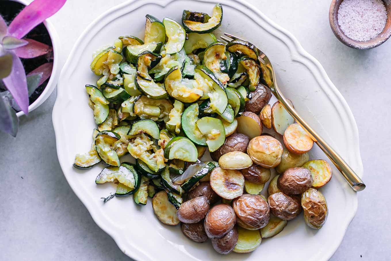roasted zucchini and potatoes on a white plate on a white table