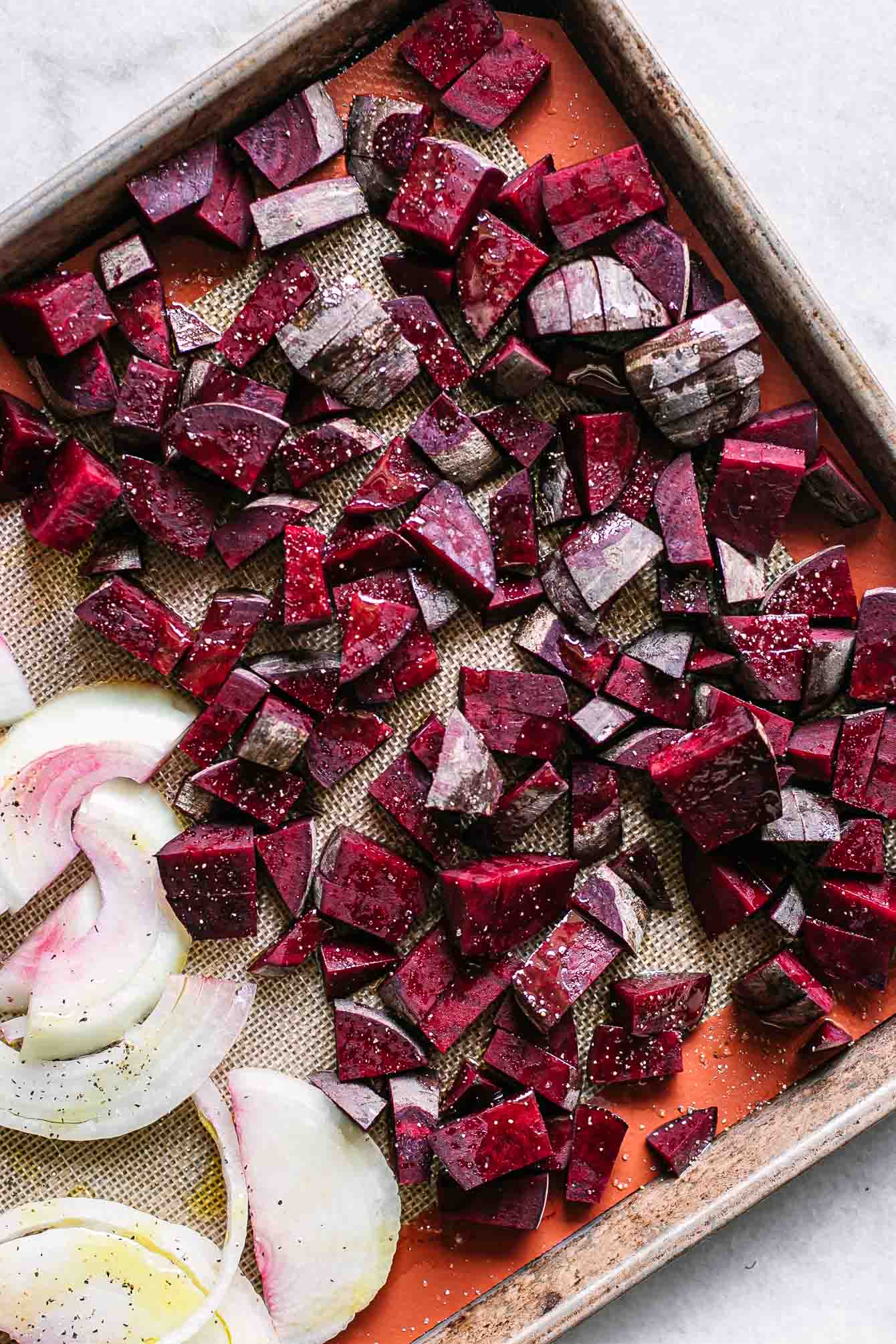 cut beets and sliced onions on a baking sheet before roasting