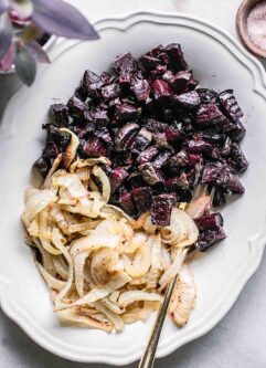 roasted beets and onions on a white serving dish on a white table