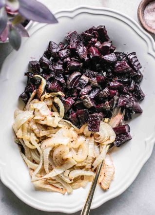 roasted beets and onions on a white serving dish on a white table