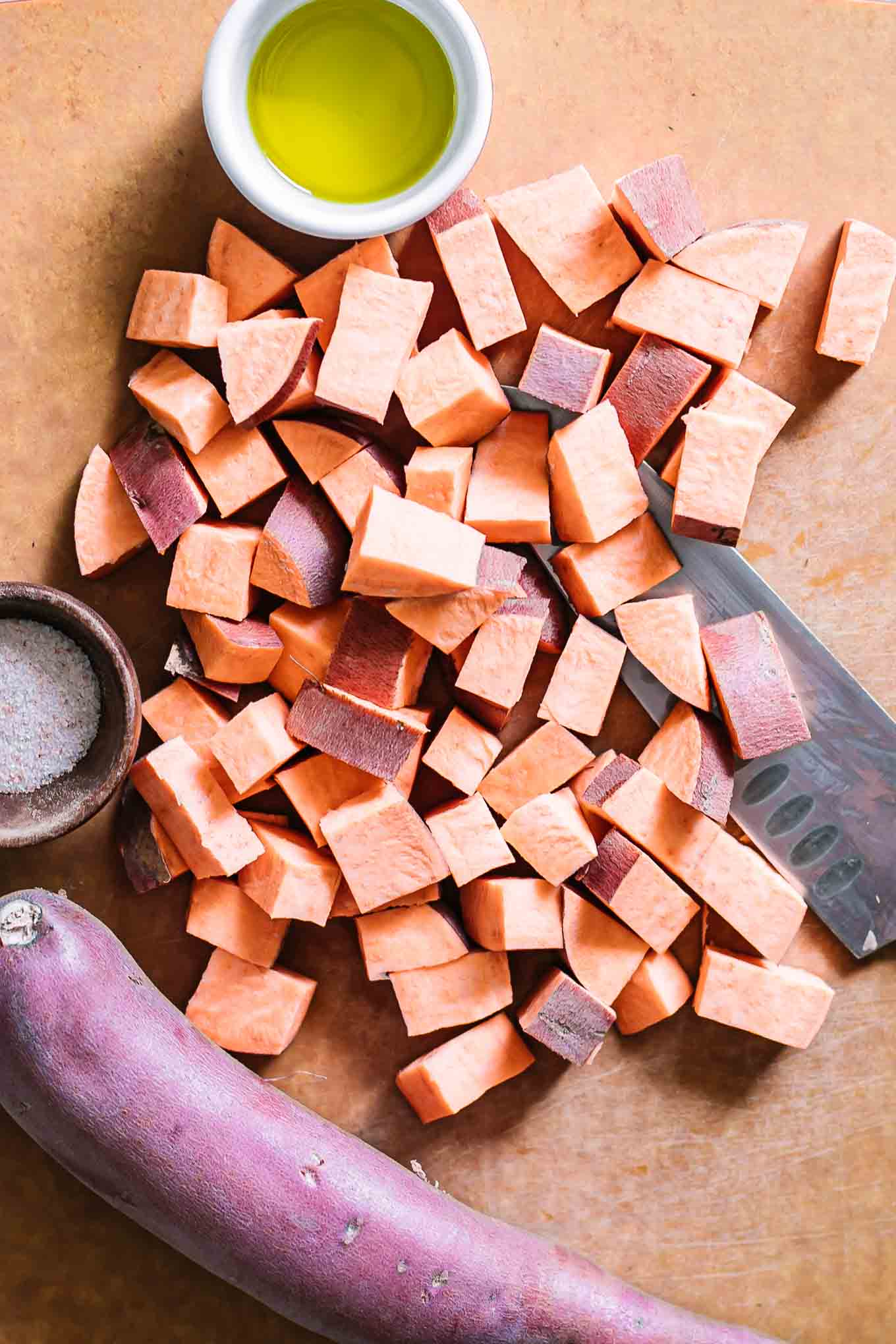 cut sweet potatoes on a cutting board before roasting