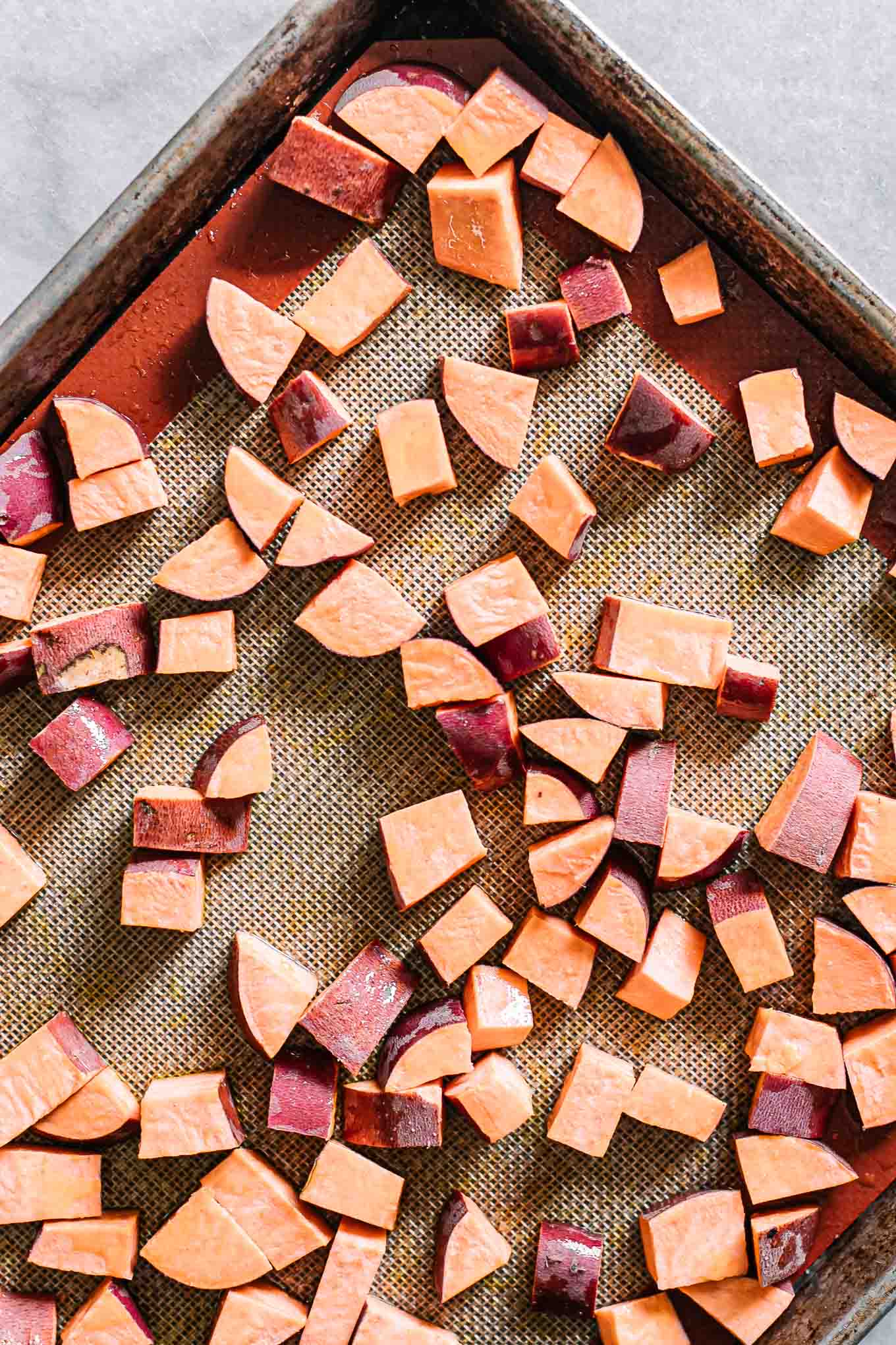 cut sweet potatoes on a sheet pan before roasting