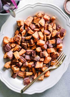 crispy baked sweet potatoes on a white plate with gold fork