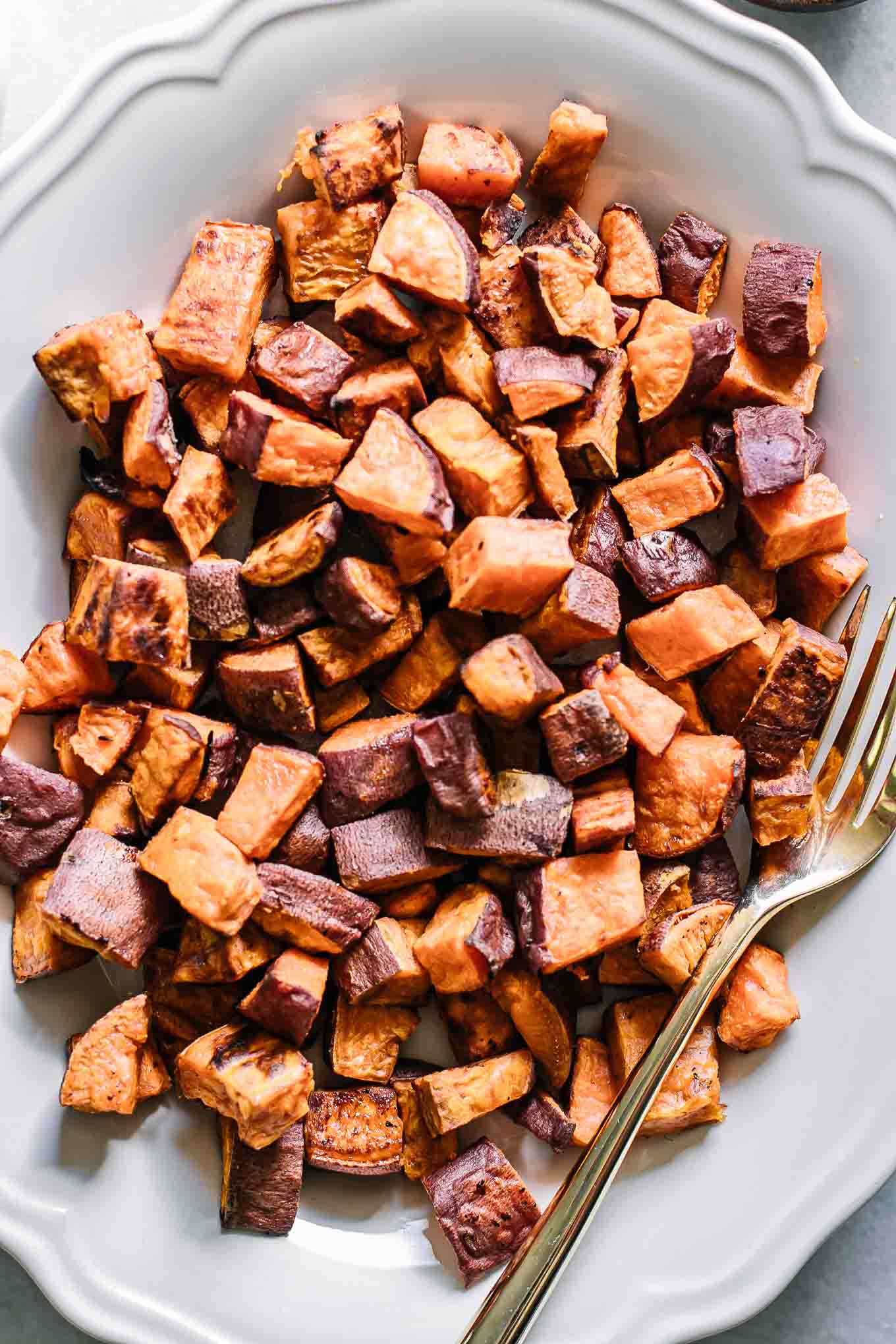 a close up photo of baked crispy sweet potatoes on a white plate