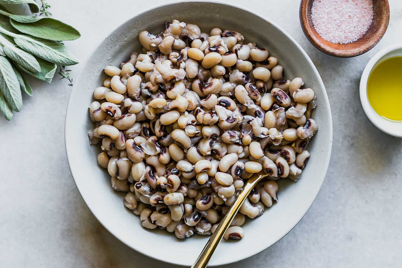 a white bowl with cooked black eyed peas on a white table