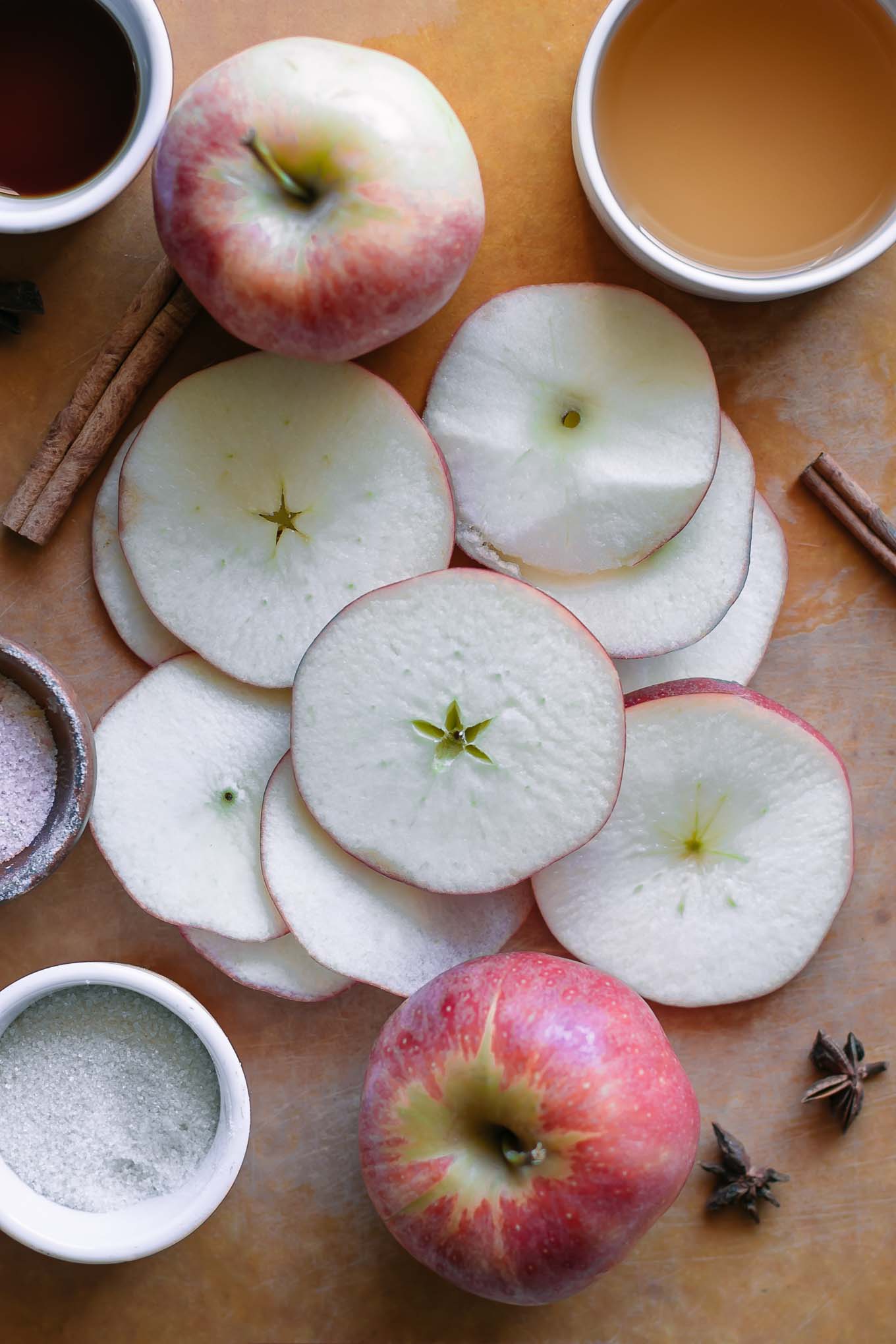 sliced apples on a cutting board with bowls of sugar, salt, and vinegar