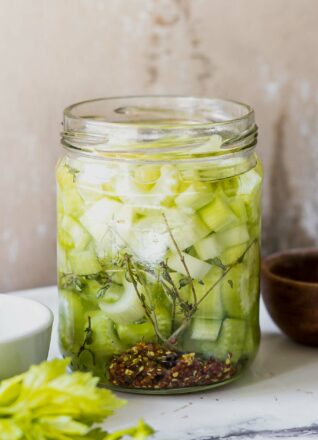 pickled celery slices in a jar on a white table