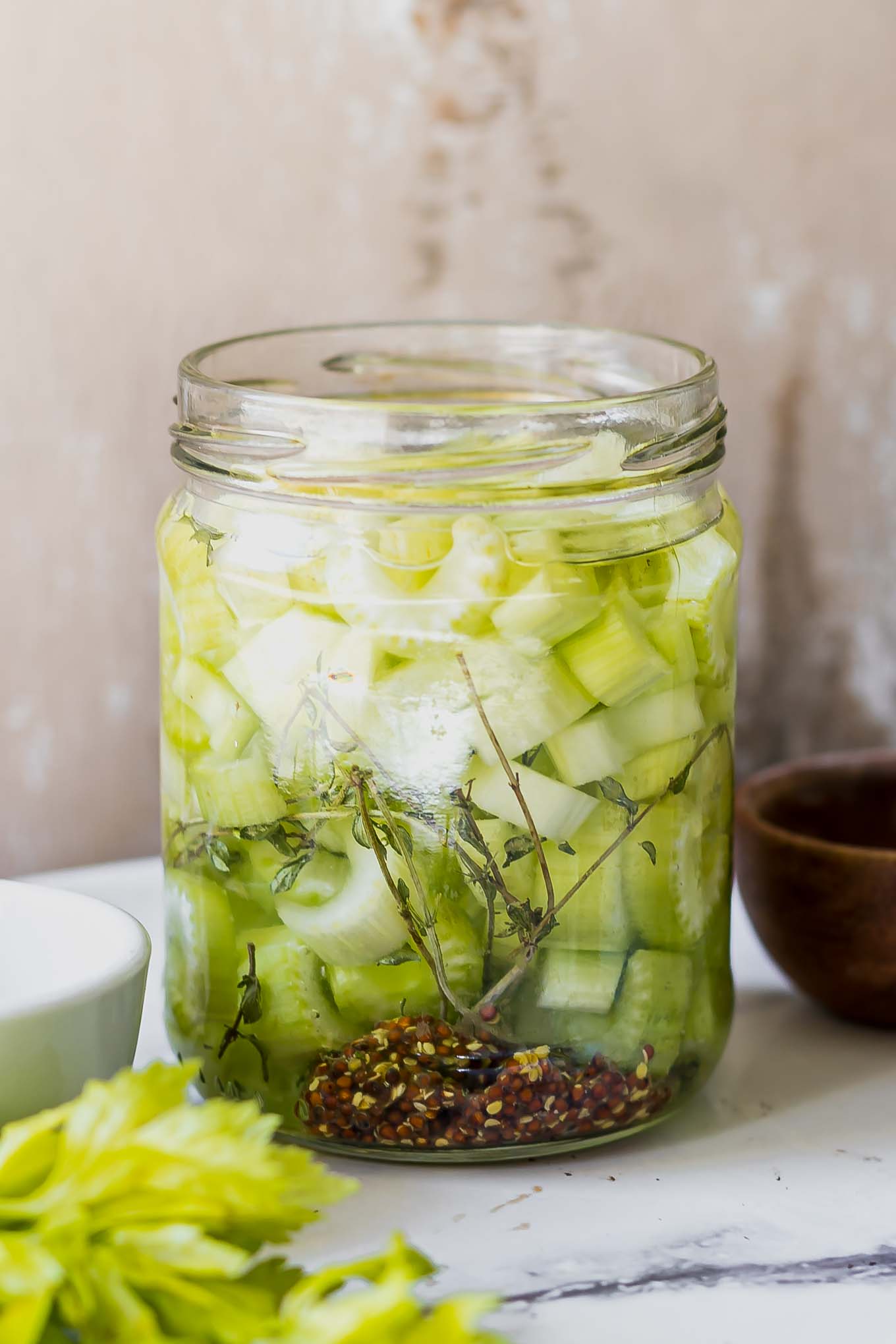 pickled celery slices in a jar on a white table