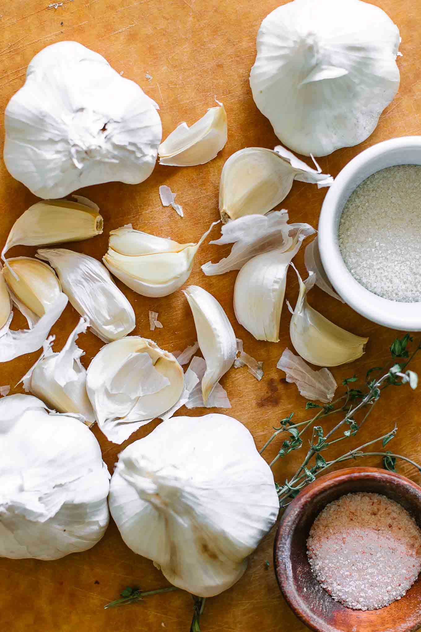 garlic cloves on a cutting board with sugar and salt bowls