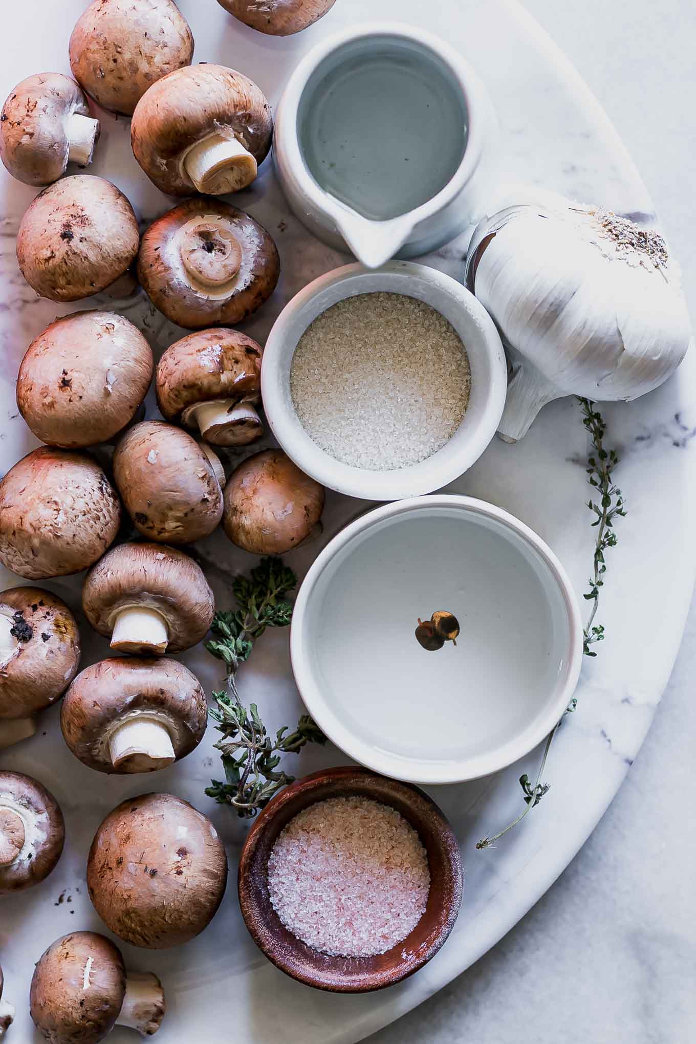 mushrooms, water, vinegar, garlic, salt, sugar, and herbs on a white table