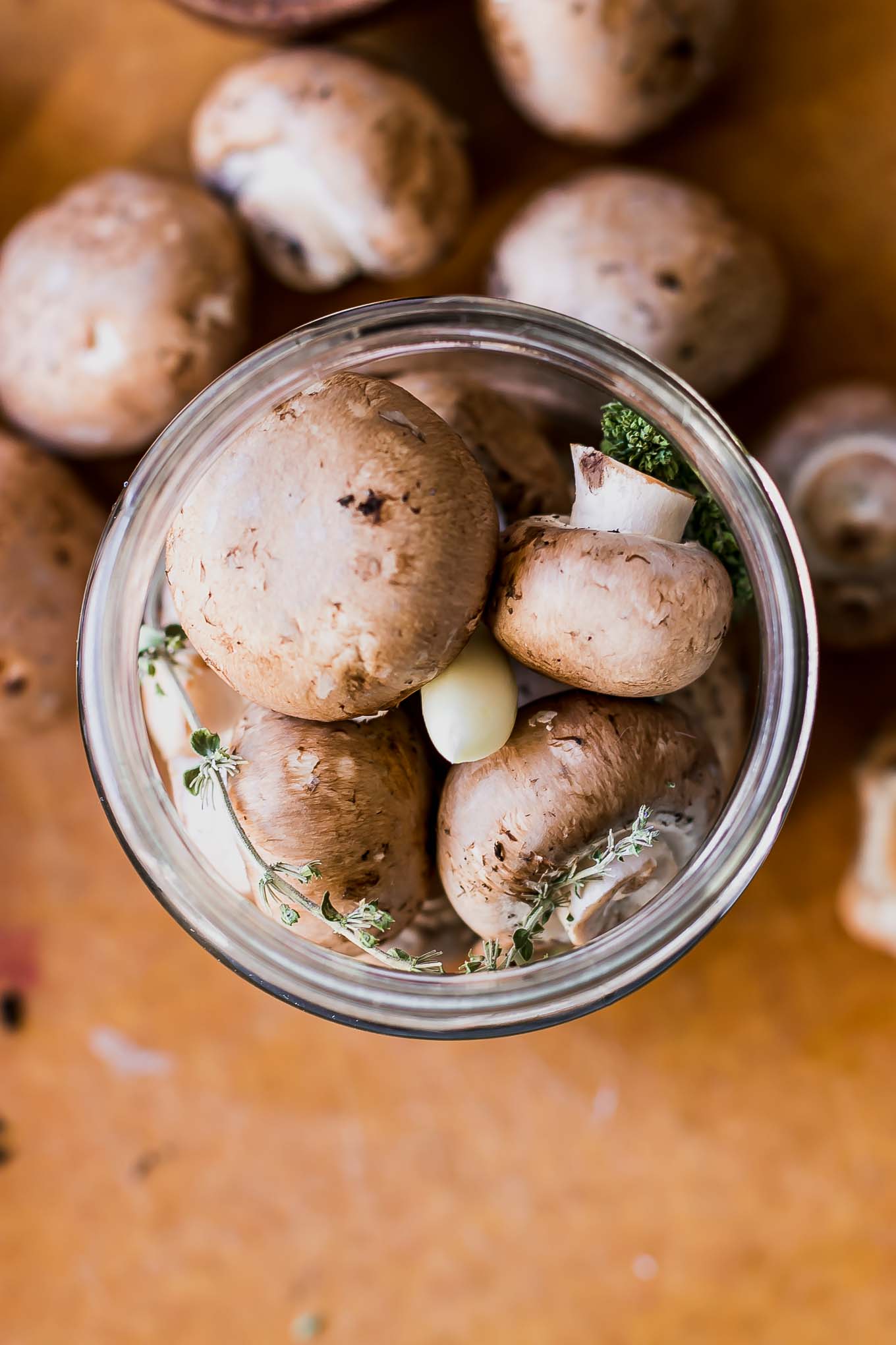 mushrooms in a jar with garlic and herbs before pickling