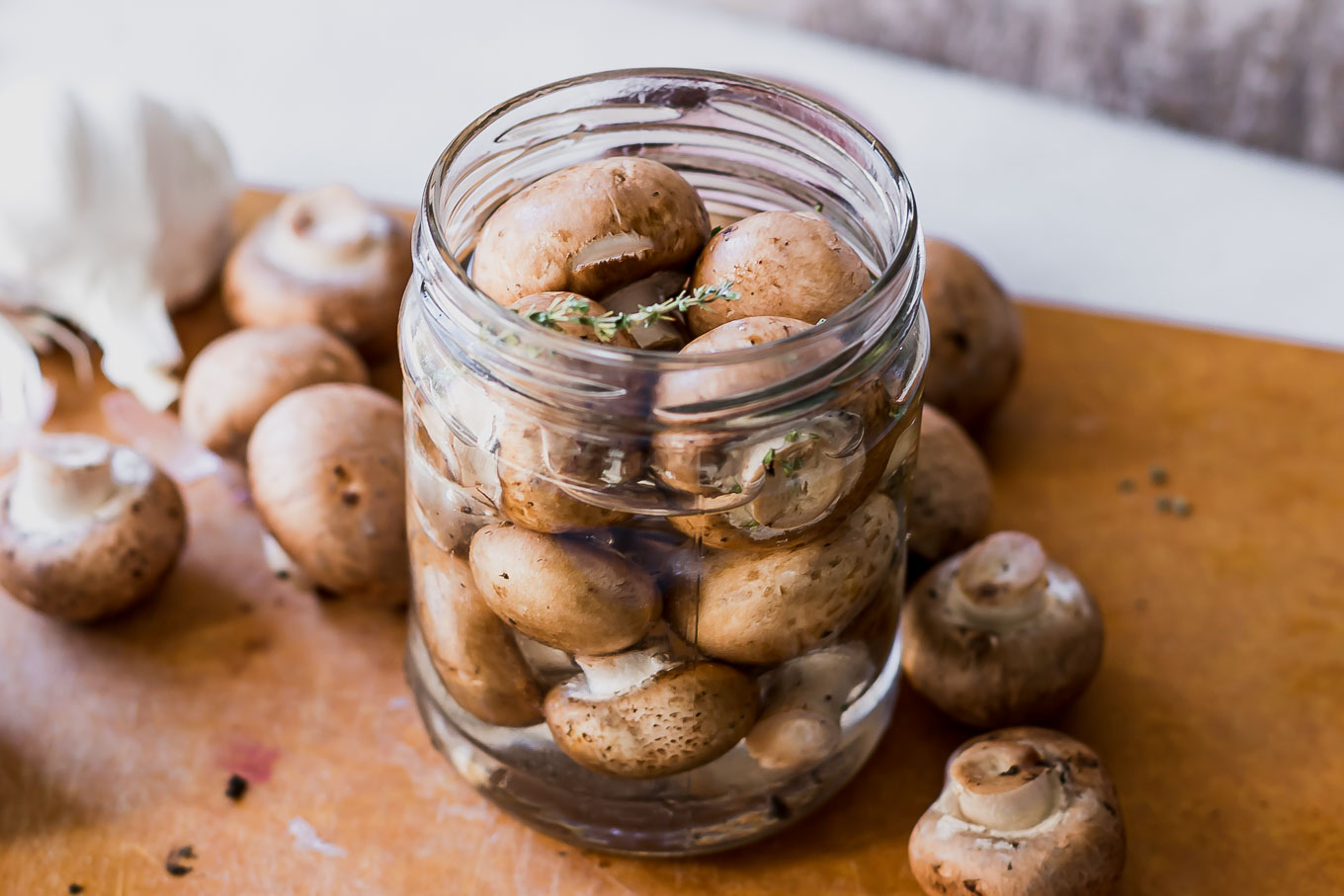 quick pickled mushrooms in a jar with vinegar brine on a wood table