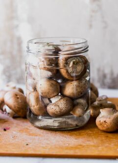 a jar of pickled mushrooms on a wood table
