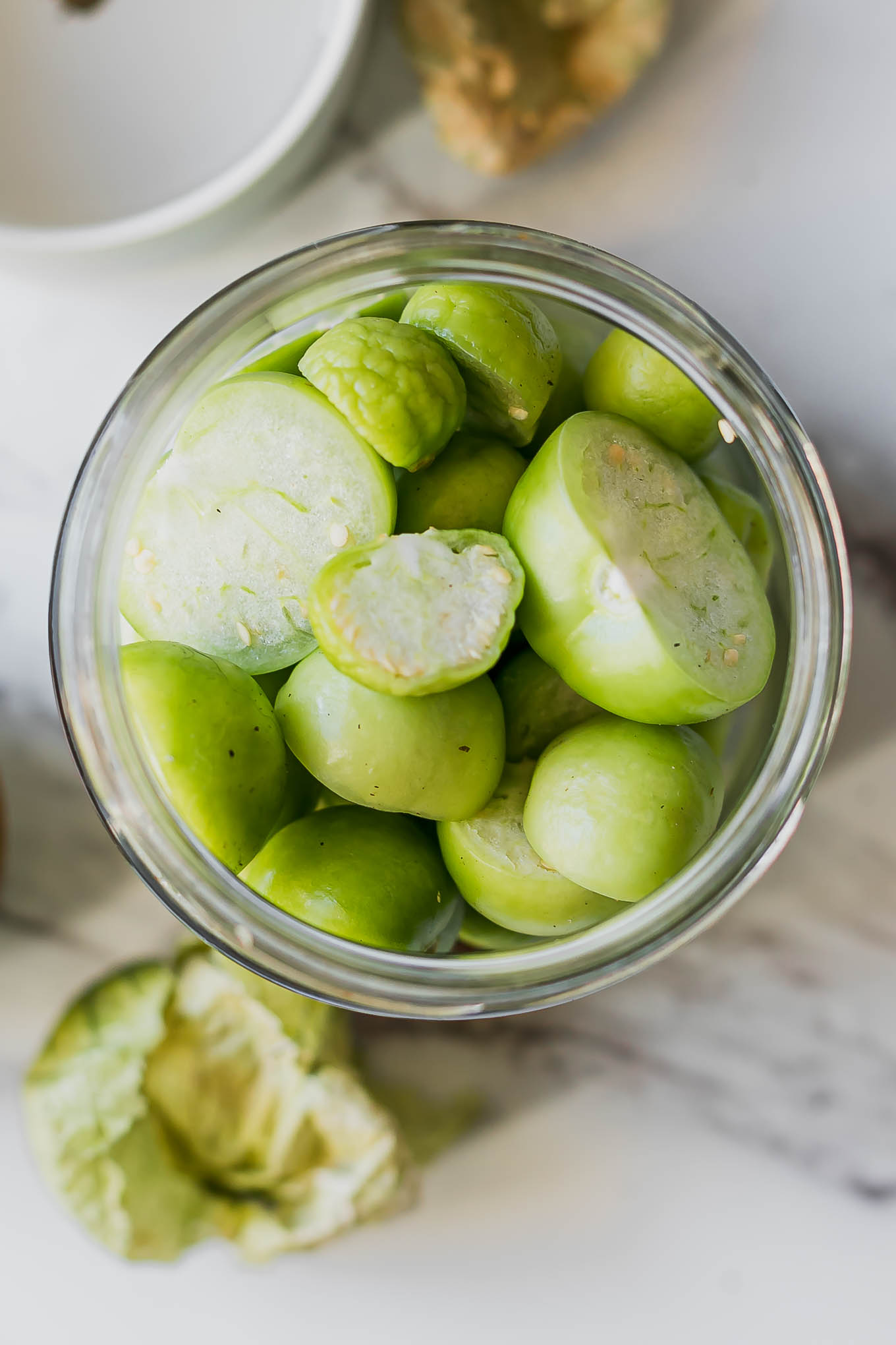 cut tomatillos in a jar before pickling