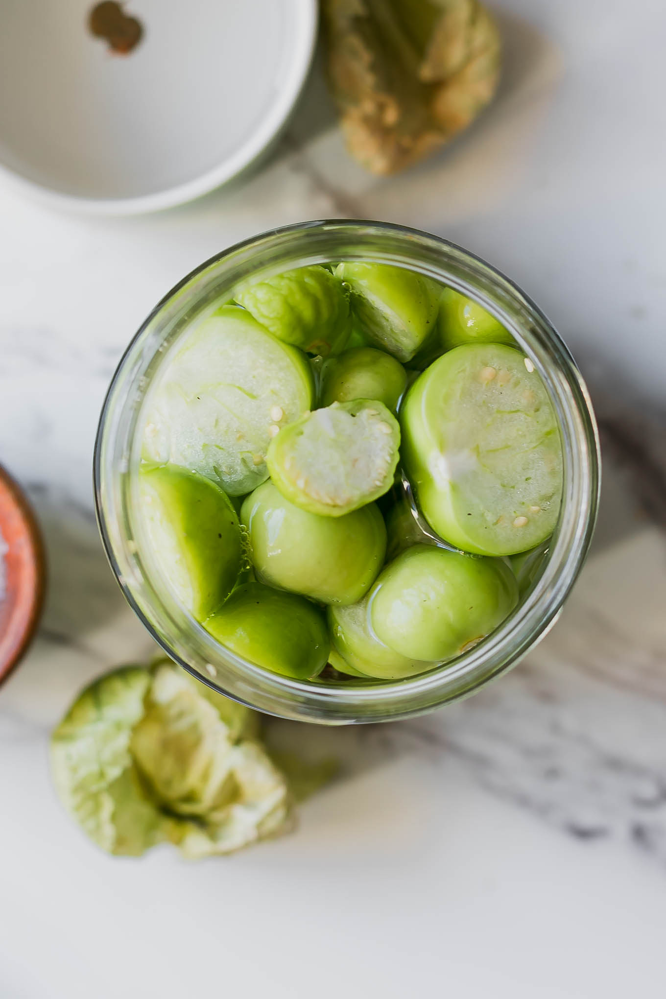 pickled tomatillos in a jar on a white table