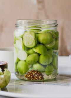 a jar of quick pickled tomatillos on a white table