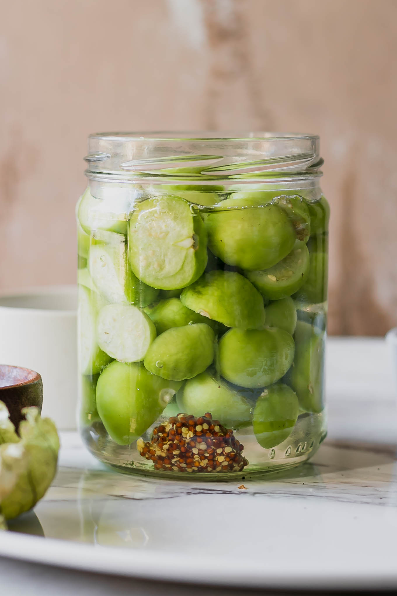 a jar of quick pickled tomatillos on a white table