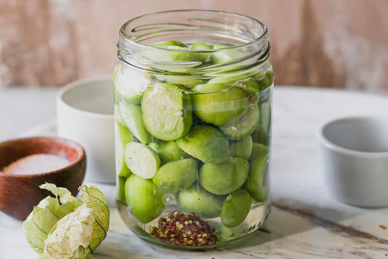 refrigerator pickled tomatillos in a jar on a white table