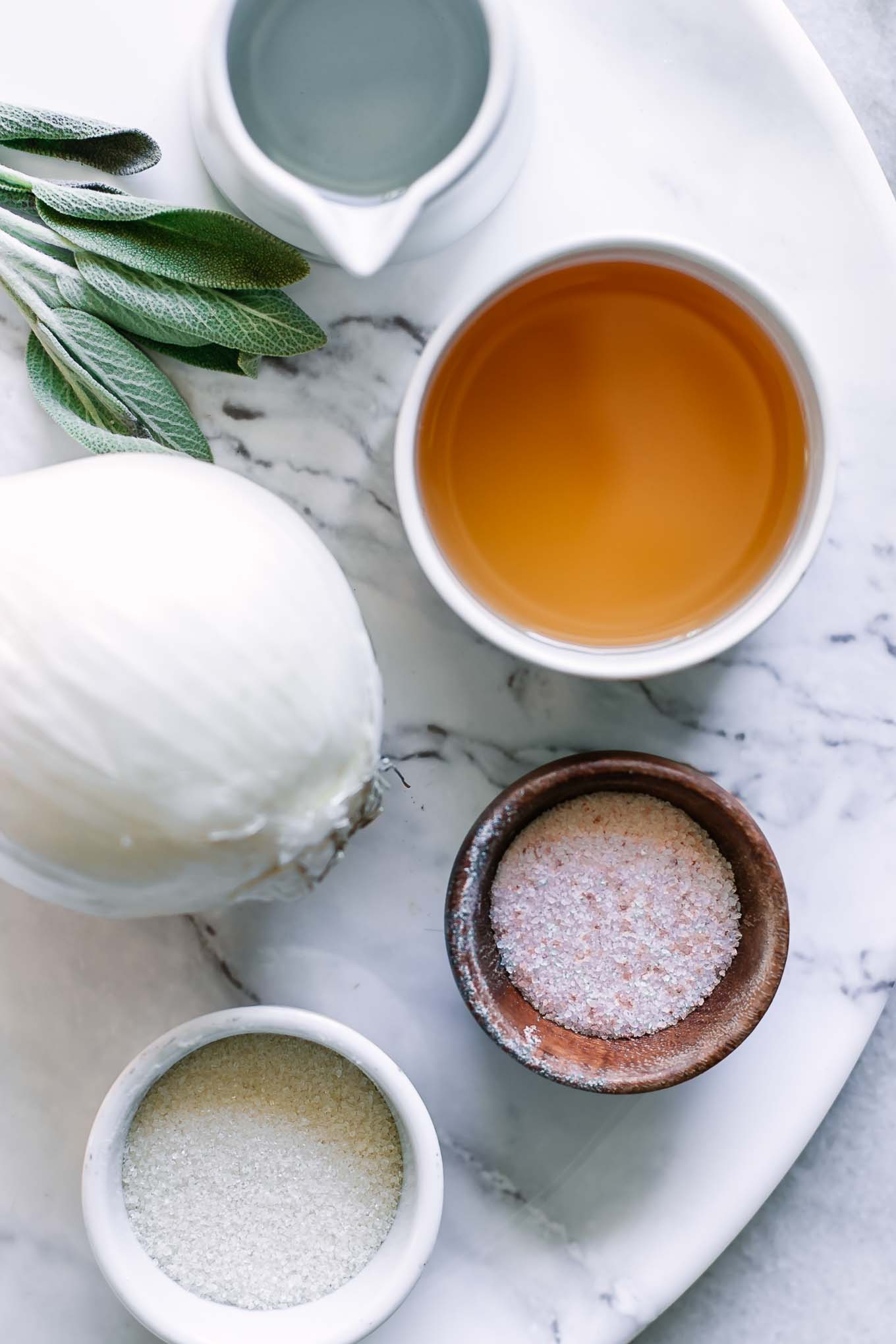 an onion and bowls of water, vinegar, salt, and sugar on a table for pickling