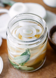 pickled white onions in a glass jar with herbs