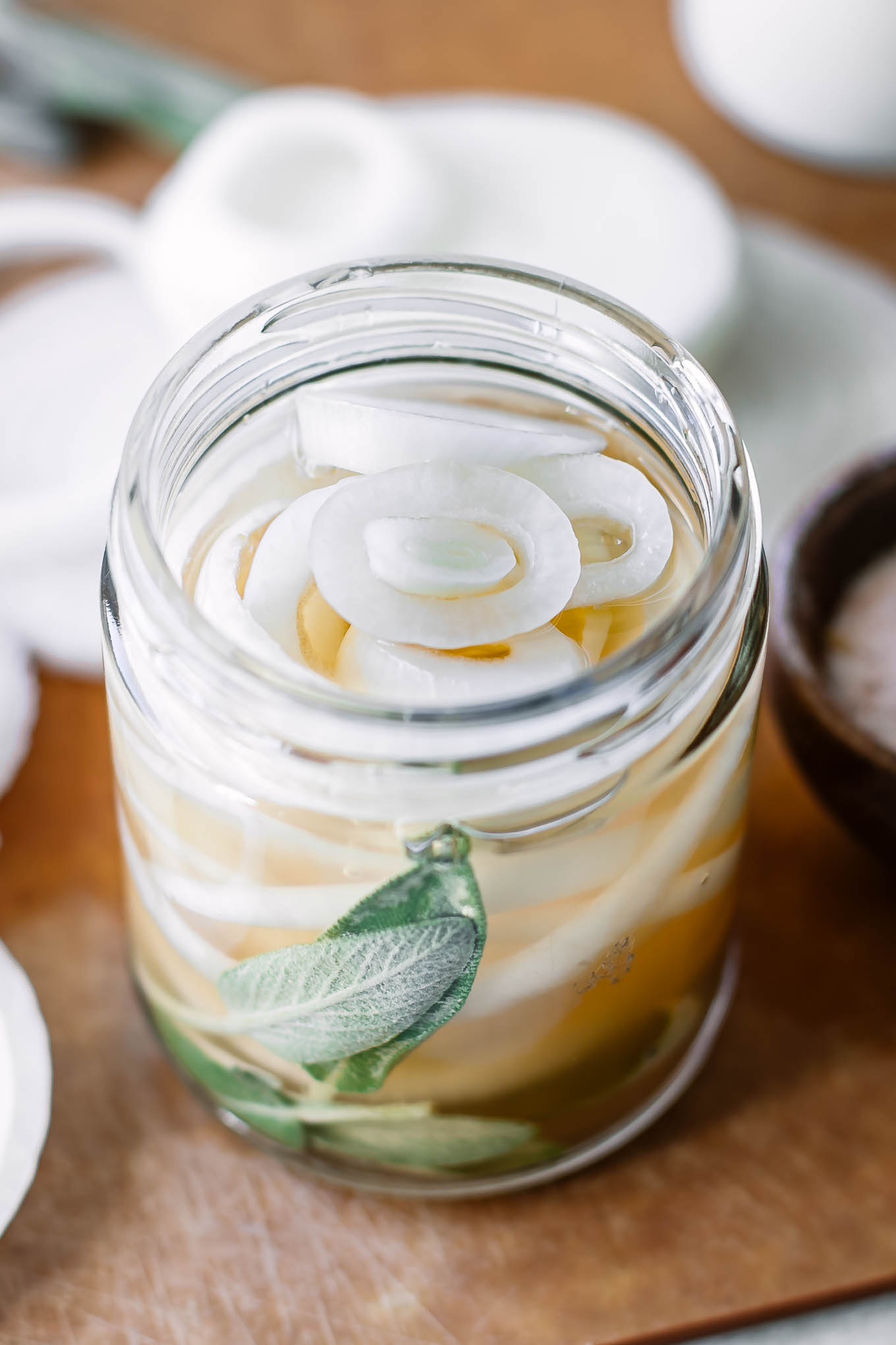pickled white onions in a glass jar with herbs