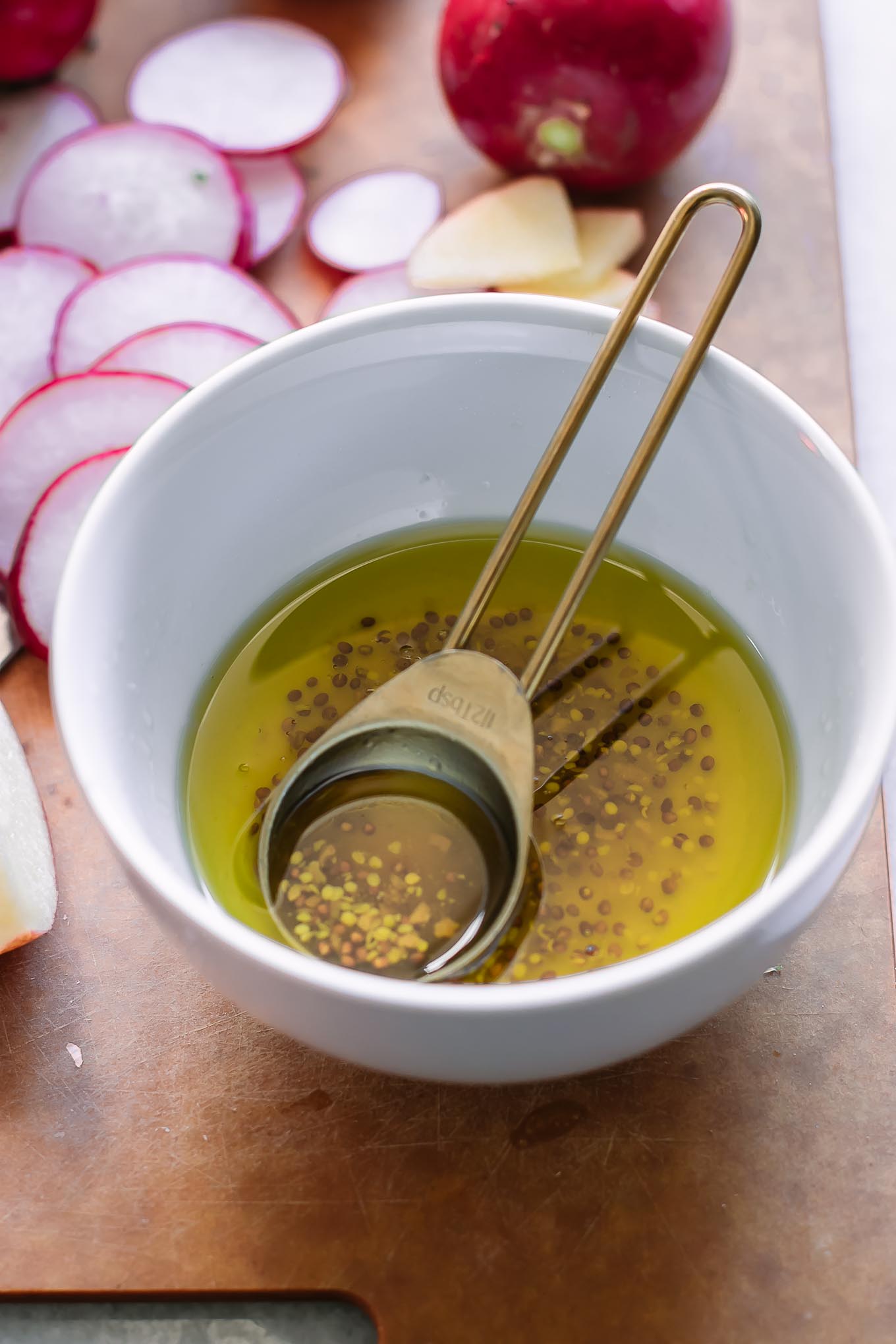 homemade salad dressing in a bowl with a gold teaspoon